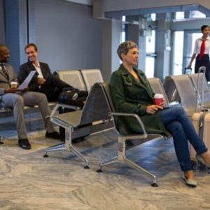 Woman sitting with luggage at waiting area in airport terminal